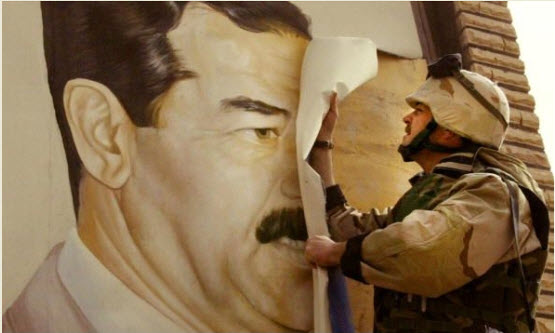 جندي أمريكي يزيل صورة صدام حسين عند دخولهم مدينة صفوان في 21 – 3 – 2003